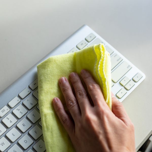 person wiping down keyboard